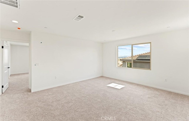 unfurnished room featuring light colored carpet, visible vents, and baseboards