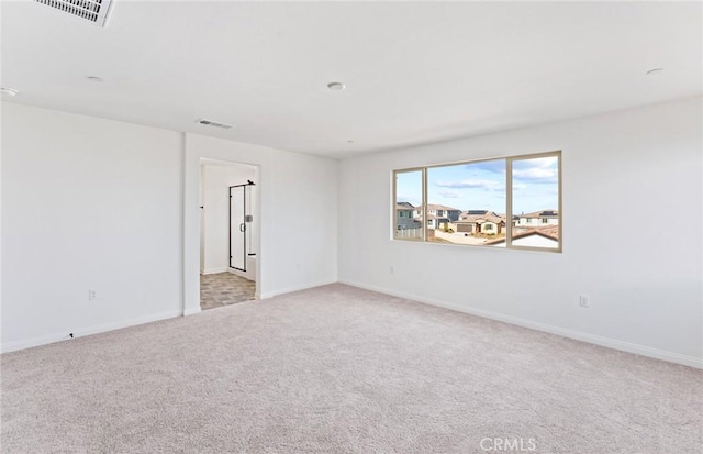 spare room with light carpet, baseboards, and visible vents