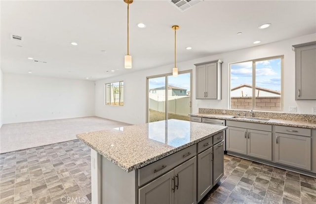 kitchen with a center island, gray cabinets, visible vents, and a sink