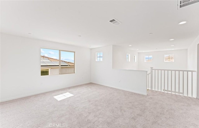 carpeted empty room featuring baseboards, visible vents, and recessed lighting