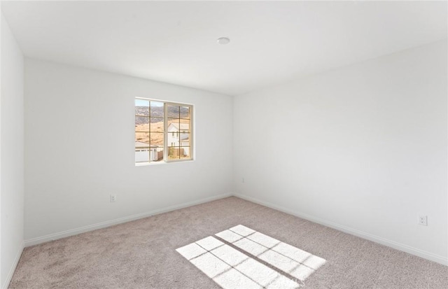 spare room featuring carpet flooring and baseboards