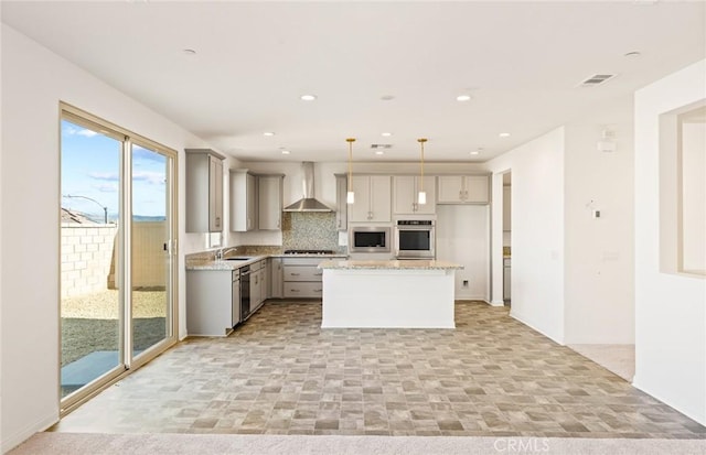 kitchen with wall chimney exhaust hood, hanging light fixtures, stainless steel appliances, gray cabinetry, and a sink