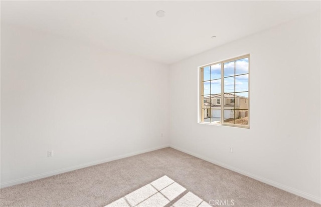 carpeted empty room featuring baseboards