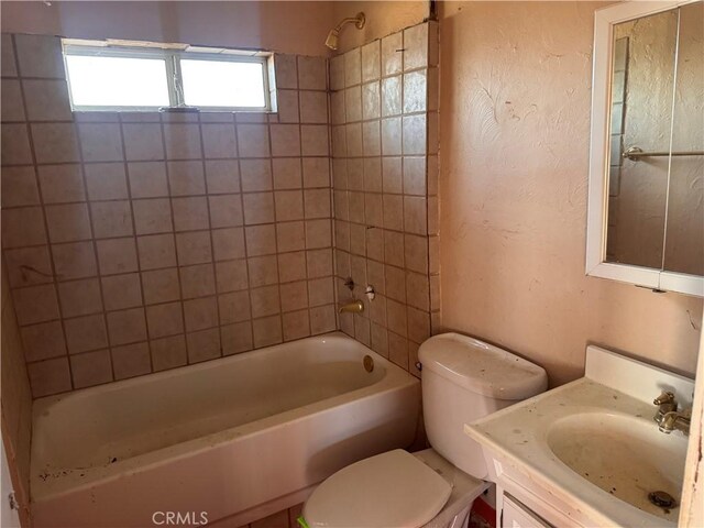 bathroom with vanity, toilet, bathing tub / shower combination, and a textured wall