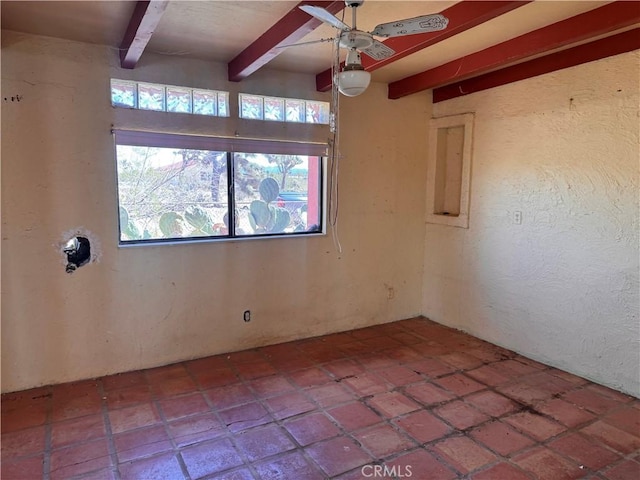 empty room with beam ceiling, a ceiling fan, and a textured wall