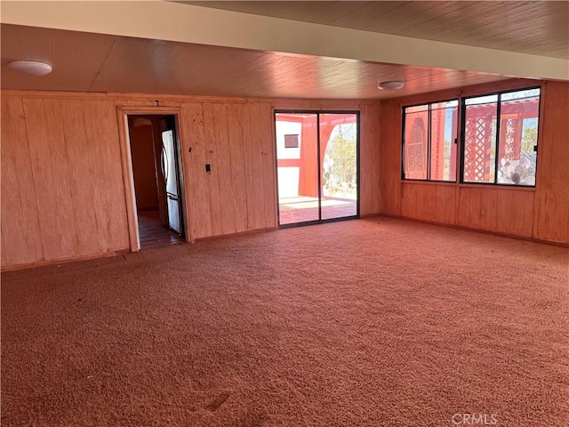 carpeted spare room featuring wood ceiling and wood walls