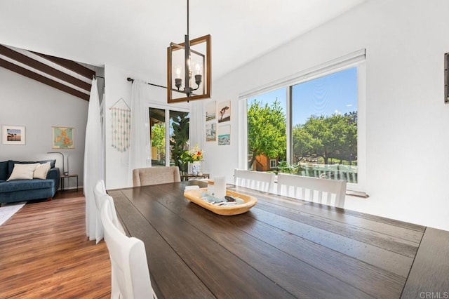 dining room featuring a notable chandelier, lofted ceiling with beams, and wood finished floors