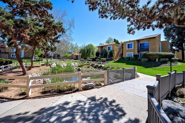 exterior space with a residential view, fence, a front lawn, and stucco siding