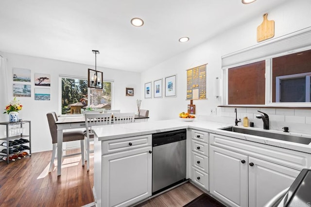 kitchen featuring dark wood-type flooring, white cabinets, a sink, dishwasher, and a peninsula