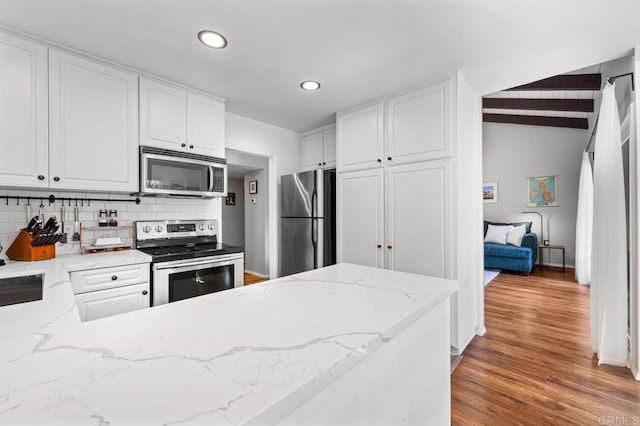 kitchen with stainless steel appliances, light wood-style floors, white cabinets, and decorative backsplash