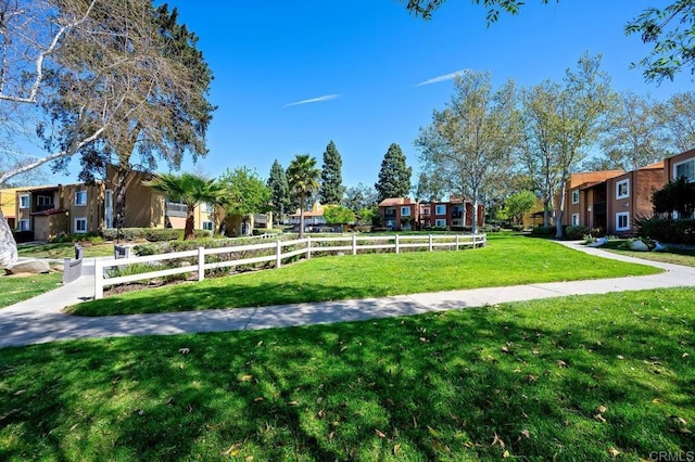 view of home's community with a residential view, a yard, and fence