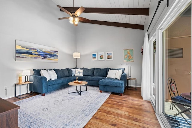 living area featuring vaulted ceiling with beams, light wood-style floors, ceiling fan, and baseboards