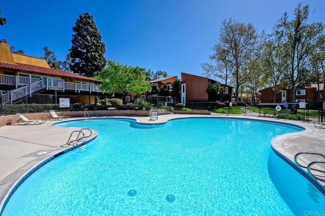 pool with a patio area, a residential view, and fence