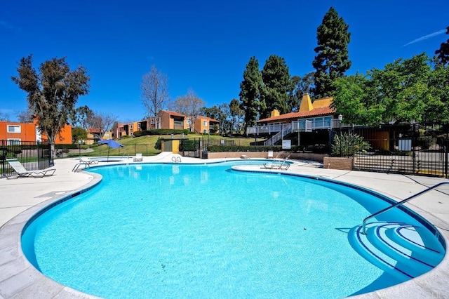 community pool with fence and a patio