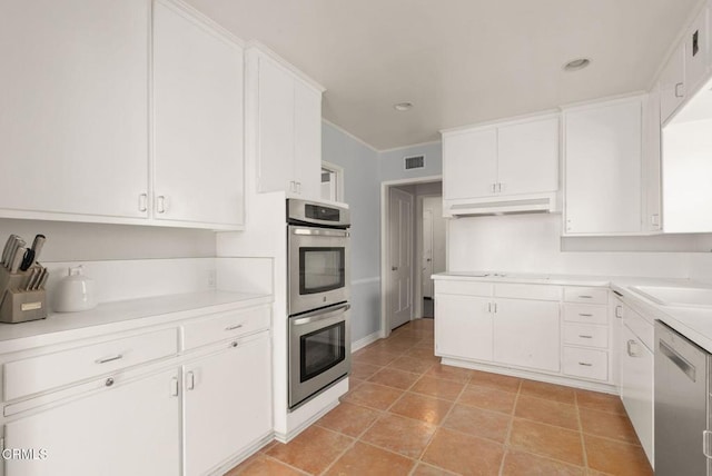 kitchen with under cabinet range hood, appliances with stainless steel finishes, white cabinets, and light countertops