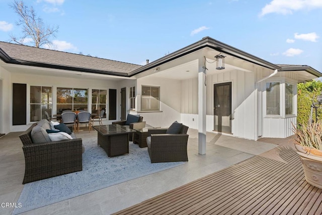 exterior space featuring an outdoor living space, board and batten siding, roof with shingles, and a patio