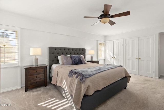 bedroom featuring two closets, baseboards, and light colored carpet