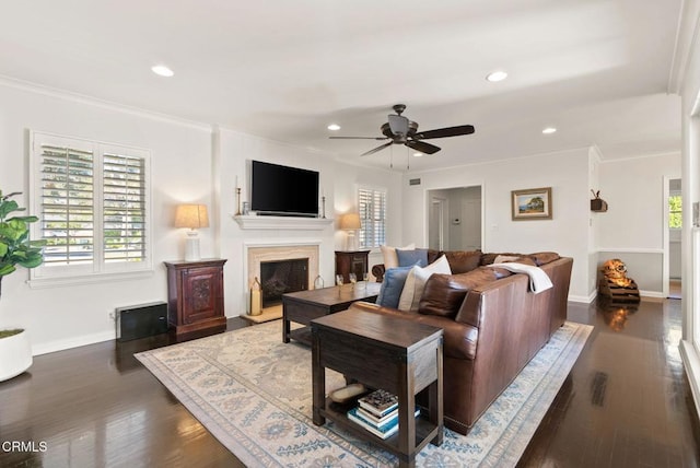 living area with baseboards, dark wood-type flooring, a fireplace with raised hearth, and crown molding