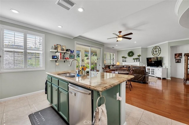 kitchen featuring dishwasher, an island with sink, ornamental molding, green cabinets, and a sink