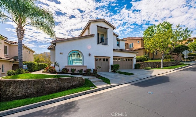 mediterranean / spanish-style home with a garage, driveway, a tiled roof, and stucco siding