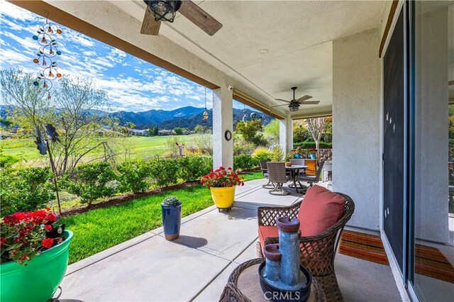 view of patio featuring ceiling fan, a mountain view, and outdoor dining area