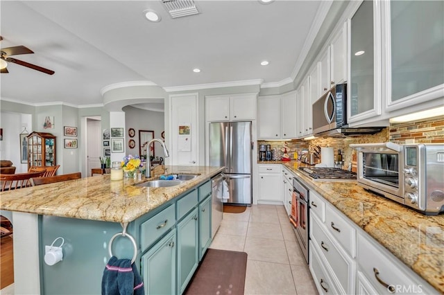 kitchen with light tile patterned floors, stainless steel appliances, a sink, white cabinetry, and decorative backsplash