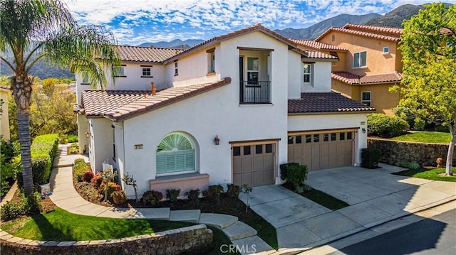 mediterranean / spanish home featuring a garage, driveway, a mountain view, and stucco siding