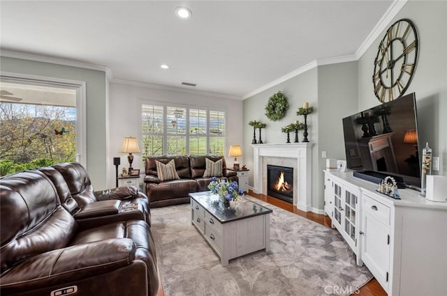 living room with light wood finished floors, recessed lighting, visible vents, ornamental molding, and a high end fireplace