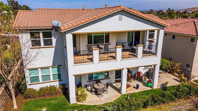 back of house with a tile roof, a patio, and stucco siding