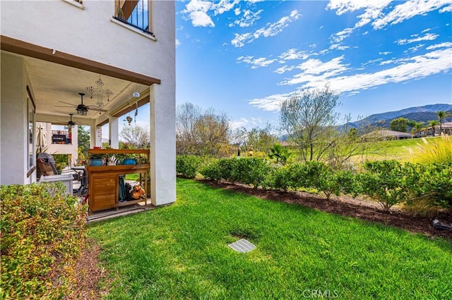 view of yard with a mountain view and a ceiling fan