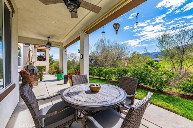 view of patio featuring ceiling fan, a mountain view, and outdoor dining space