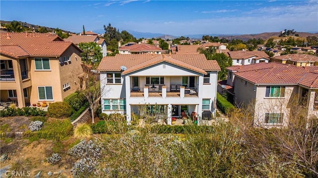 back of house with a tiled roof, a balcony, a residential view, and stucco siding