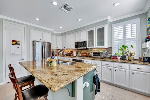 kitchen with a sink, white cabinetry, visible vents, appliances with stainless steel finishes, and crown molding