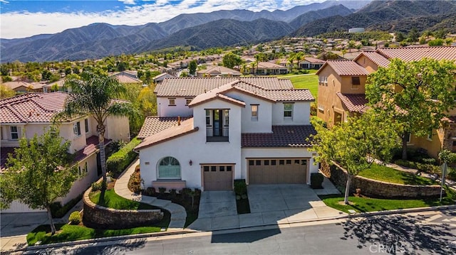 view of front of property with concrete driveway, a residential view, a tiled roof, an attached garage, and a mountain view