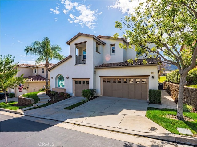 mediterranean / spanish-style house featuring driveway, a tiled roof, a garage, and stucco siding