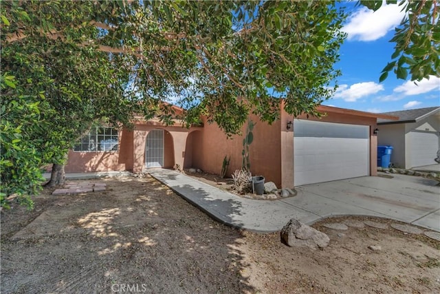 view of front facade featuring an attached garage, concrete driveway, and stucco siding