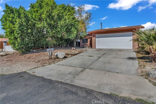 view of front of property featuring a garage, concrete driveway, and stucco siding