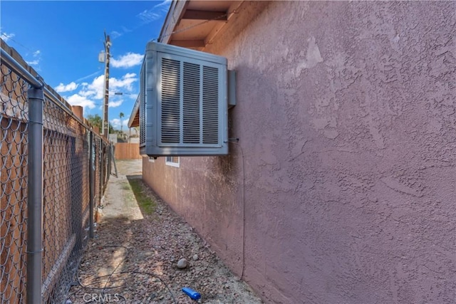 view of property exterior with fence, cooling unit, and stucco siding