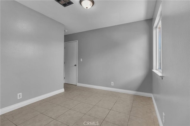 empty room with light tile patterned floors, baseboards, and visible vents