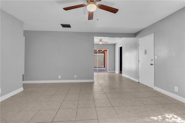 empty room with a ceiling fan, light tile patterned flooring, visible vents, and baseboards