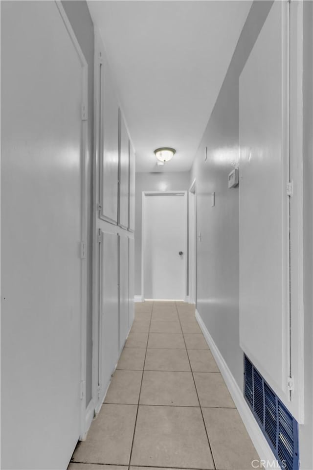 hallway with light tile patterned floors, baseboards, and visible vents