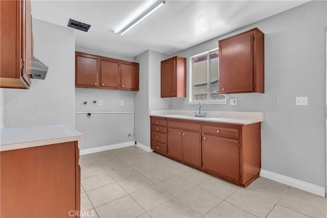 kitchen featuring wall chimney range hood, visible vents, light countertops, and a sink