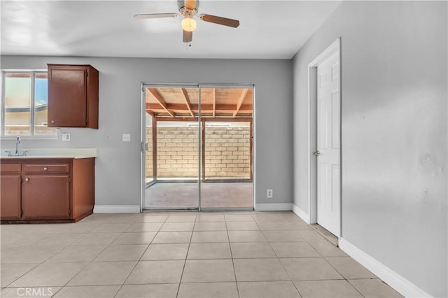 kitchen with ceiling fan, light tile patterned flooring, a sink, baseboards, and light countertops