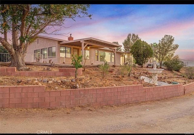 view of front of property with a chimney and stucco siding