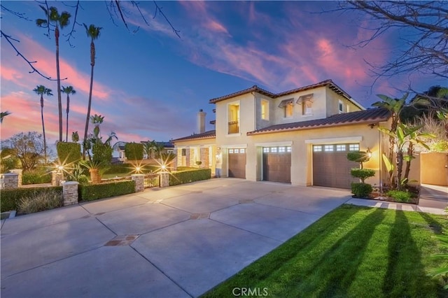 mediterranean / spanish house with driveway, an attached garage, a tile roof, and stucco siding