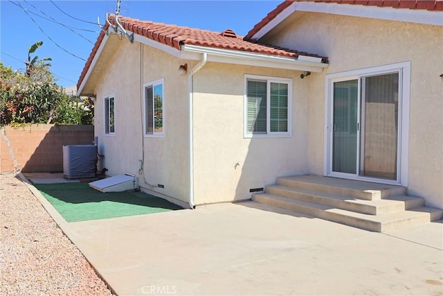 view of side of home with a patio, entry steps, central AC, fence, and a tiled roof