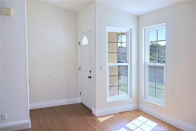 foyer entrance with light wood-style flooring, plenty of natural light, visible vents, and baseboards