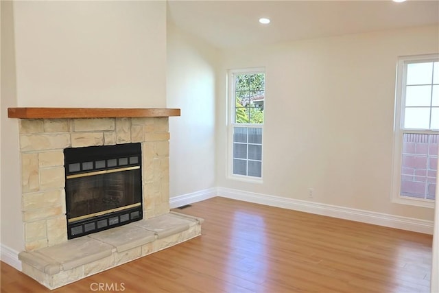 unfurnished living room featuring recessed lighting, a fireplace, wood finished floors, and baseboards