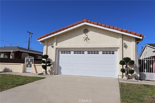 view of front of house featuring driveway, an attached garage, a gate, fence, and stucco siding