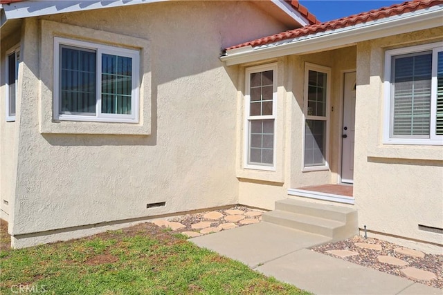 property entrance featuring a tiled roof, crawl space, and stucco siding